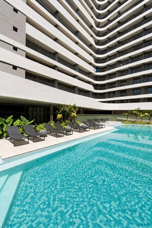 A modern hotel with a multi-level pool area, lounge chairs, and a clear blue pool. - Onde a Privacidade Encontra a Elegância República (Santa Ifigênia)