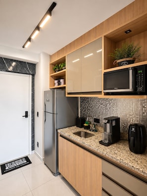 A modern kitchen with a refrigerator, microwave, coffee maker, and a sink. - Vista para a Praça da República | Ao lado do Metrô (Santa Ifigênia)