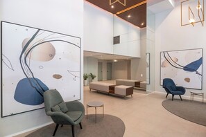 A modern interior with abstract art, a sofa, two chairs, and a small table. - Vista aberta | Luz natural 650m do Metrô Brooklin (São Paulo)
