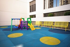 A children's play area with colorful play structures and yellow benches. - Vista aberta | Luz natural 650m do Metrô Brooklin (São Paulo)