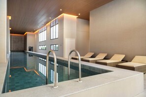 Ein moderner, überdachter Innenpool mit Liegestühlen.