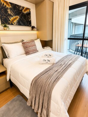 A hotel room with a bed, a bedside table, a nightstand, a window with curtains, and a view of the outside balcony. - Conforto | Estilo | Metrô República (Santa Ifigênia)