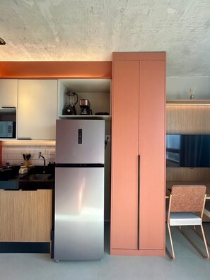 Et moderne køkken med et rustfrit stål køleskab, en indbygget ovn og en kaffemaskine på bordpladen.