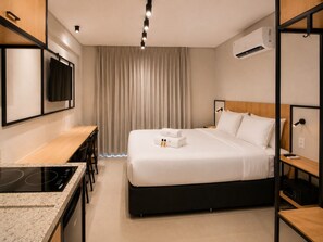 Ein Hotelzimmer mit Bett, Schreibtisch, integriertem Herd und Fernseher.