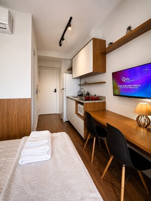 A modern hotel room with a bed, a desk, a TV, and a kitchenette. - República, Centro de São Paulo, metrô ao lado (Santa Ifigênia)