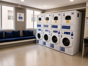 A laundry facility with four washing machines, each marked with a number and the logo 'SECA'. - Moderno e Equipado | 1 Vaga | Metrô República (São Paulo)