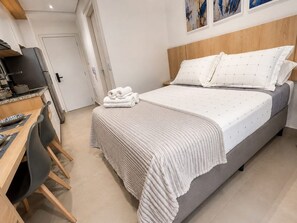 Une chambre à coucher avec un lit, une table de chevet, une chaise et un bureau avec un ordinateur.