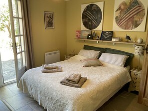 A bedroom with a bed, pillows, a nightstand, a lamp, and artwork on the wall. - Villa in Var With Swimming Pool (Cotignac)