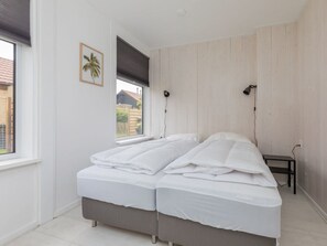 A bedroom with a double bed, a window with a view, and a small bedside table. - Holiday Home in Renesse With Swimming Pool (Renesse)