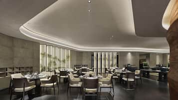 Un comedor moderno con mesas y sillas redondas, techo curvo y vistas al exterior.