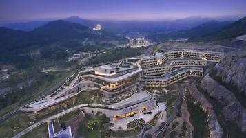 Un moderno complejo hotelero con varias edificaciones interconectadas, rodeado de un paisaje montañoso.