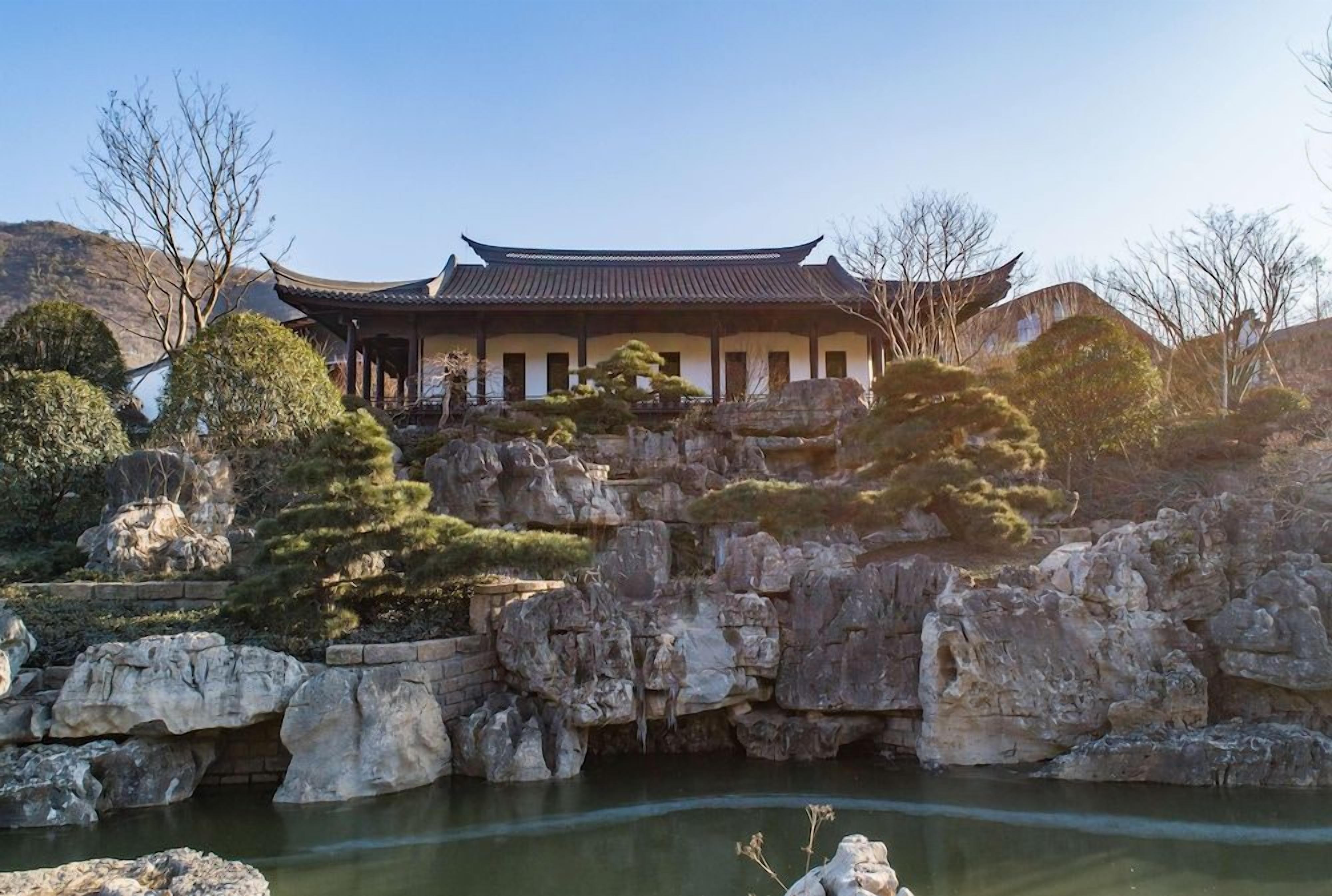 Un bâtiment traditionnel doté d’un toit incurvé, entouré d’un paysage rocheux et d’arbres.