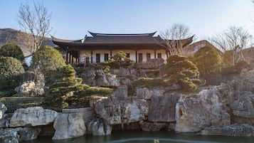 Un bâtiment traditionnel doté d’un toit incurvé, entouré d’un paysage rocheux et d’arbres.