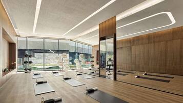 Un gimnasio moderno con colchonetas de ejercicio, un espejo grande y vistas al exterior.