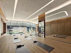 Una sala de gimnàstica moderna amb estores d'exercici, un gran mirall i vista cap a l'exterior.
