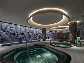 A modern indoor swimming pool area with multiple pools, a rock wall, and a unique ceiling design. - Banyan Tree Nanjing Garden Expo (Nanjing)