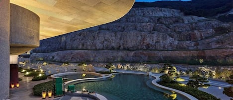 A pool area with lounge chairs and a large building structure.