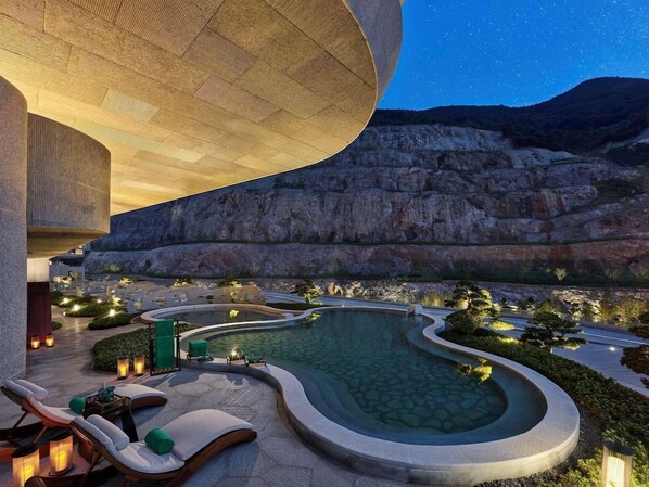 Zona de piscina con sillas de descanso y un edificio grande.