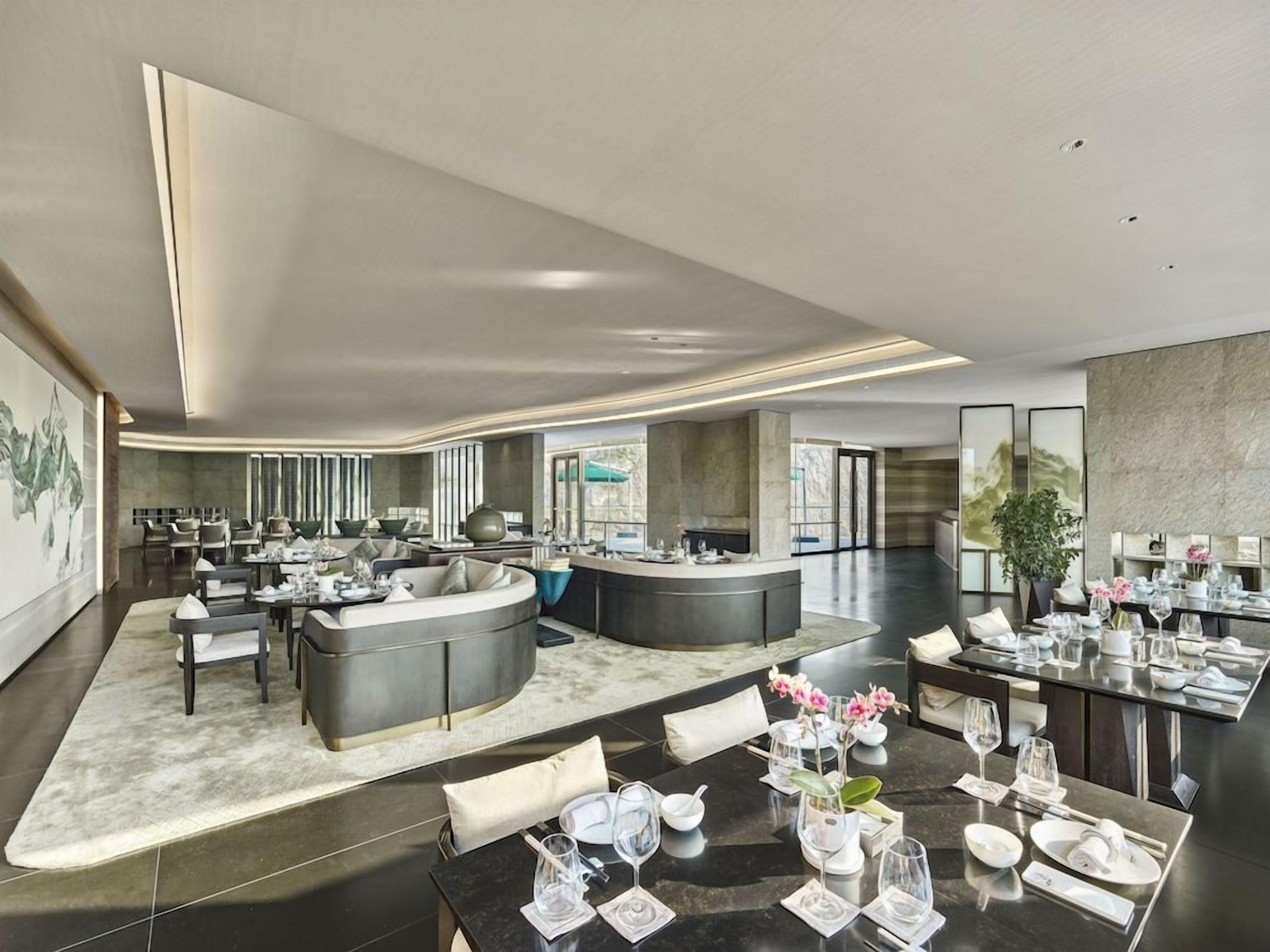 Um hall de hotel moderno com área de estar central, bar e balcão de recepção.