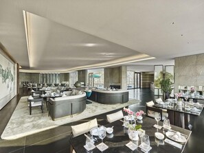 Un moderno vestíbulo de hotel con una zona de estar central, un bar y una recepción.