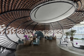 Un interior moderno con techo curvo, zonas de estar y vistas al exterior.