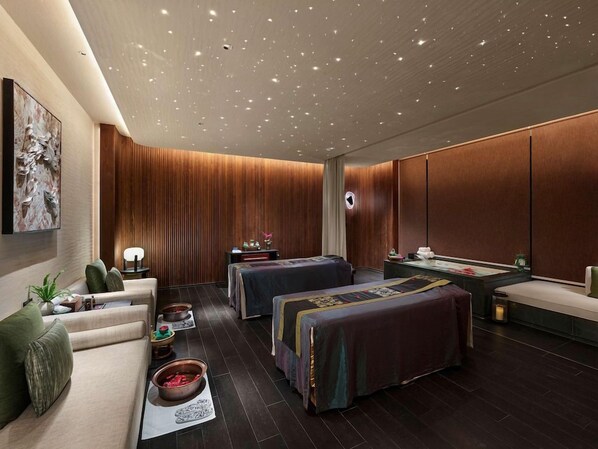Una sala de spa moderna amb sostre de fusta, dues cameres de massatge, una taula de massatge i una taquilla d'atenció al client.