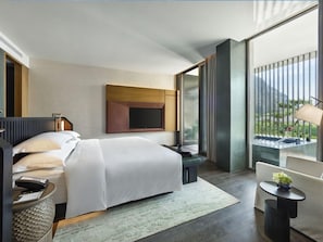 A modern hotel room with a large bed, a desk, a chair, and a balcony with a view. - Banyan Tree Nanjing Garden Expo (Nanjing)