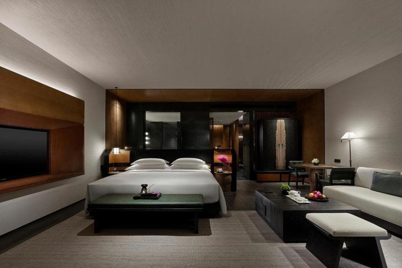 Ein modernes Hotelzimmer mit einem großen Bett, einer Couch, einem Couchtisch und einem Fernseher.
