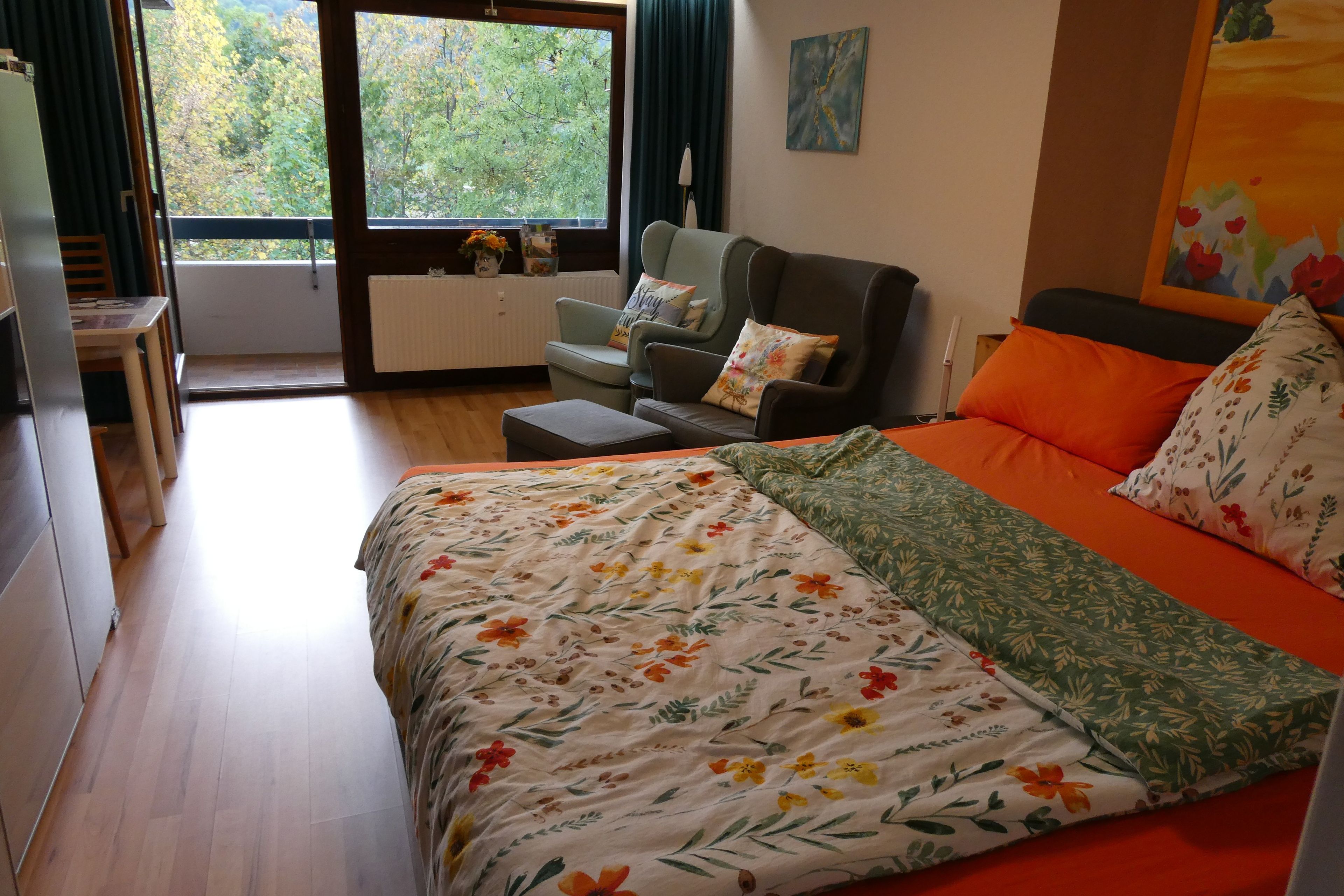 Ein Schlafzimmer mit Bett, einer Couch, einem Tisch und Blick ins Freie.