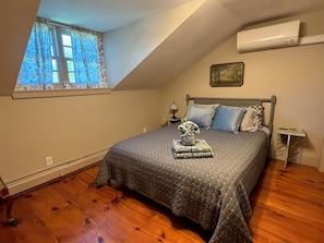 A bedroom with a bed, a window, an air conditioner, and a small table. - The Crow and Stone - Great Location (Fly Creek)