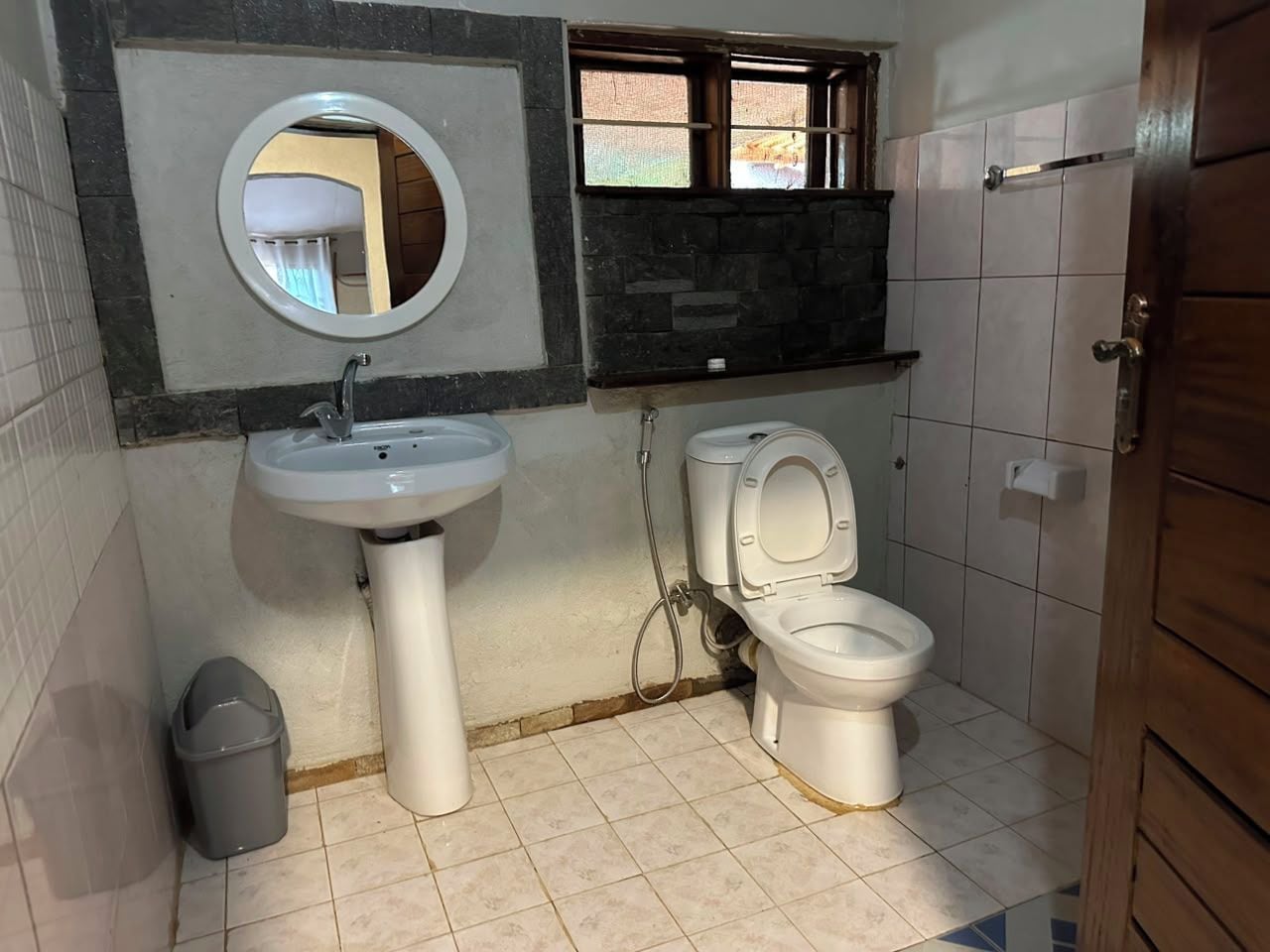 Un baño con lavamanos, inodoro y espejo.