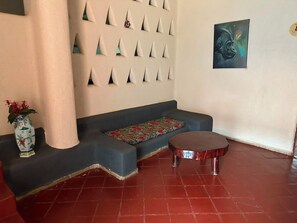 Quarto com sofá, uma mesinha, um vaso decorativo e parede com padrão geométrico.