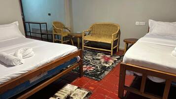Une chambre avec deux lits, une chaise, une petite table et un tapis à motifs.