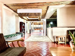 A spacious lobby with a wooden ceiling, a patterned rug, and a seating area with a bench and chairs.