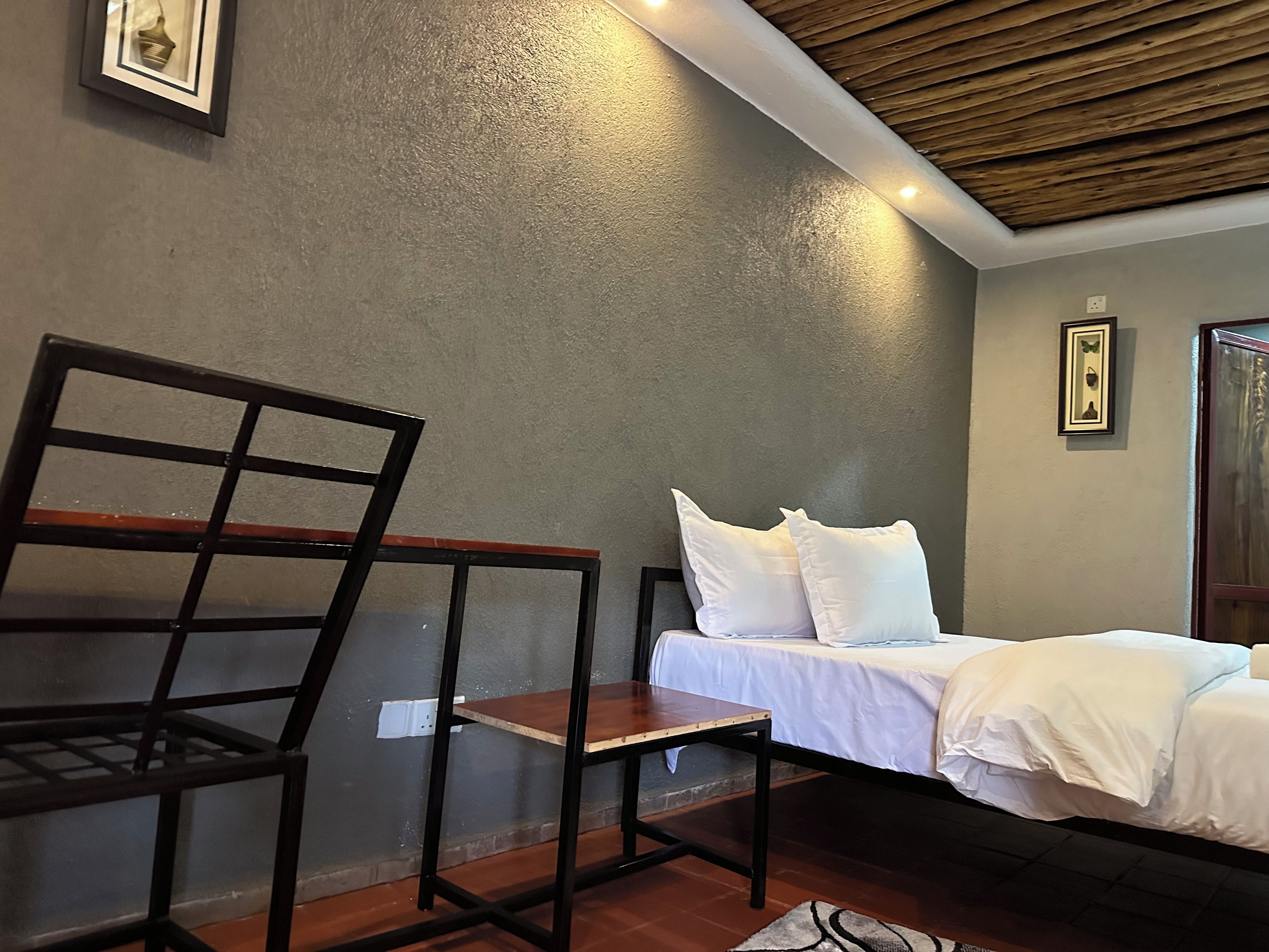 A room with a bed, a chair, and a wooden ceiling.