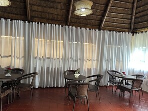 A dining area with wicker furniture and a thatched ceiling.