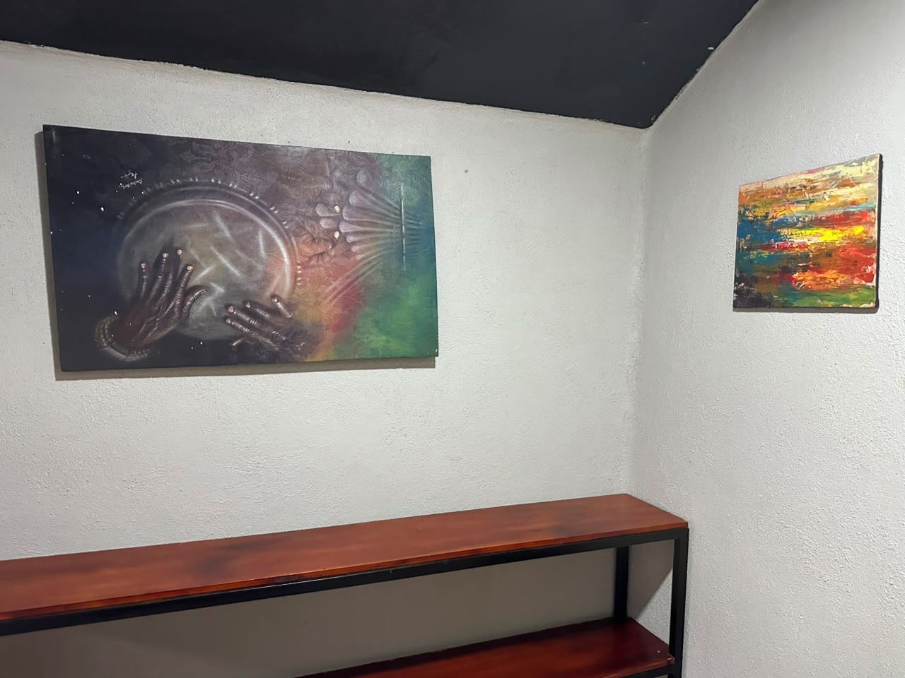 Une pièce avec un banc en bois et deux œuvres d’art accrochées au mur.