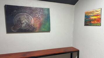 Une pièce avec un banc en bois et deux œuvres d’art accrochées au mur.