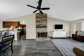 A modern kitchen with wooden cabinets, a stone fireplace, and a ceiling fan. - Lakeside Cottage - Dock, Views, Fireplace (Prudenville)