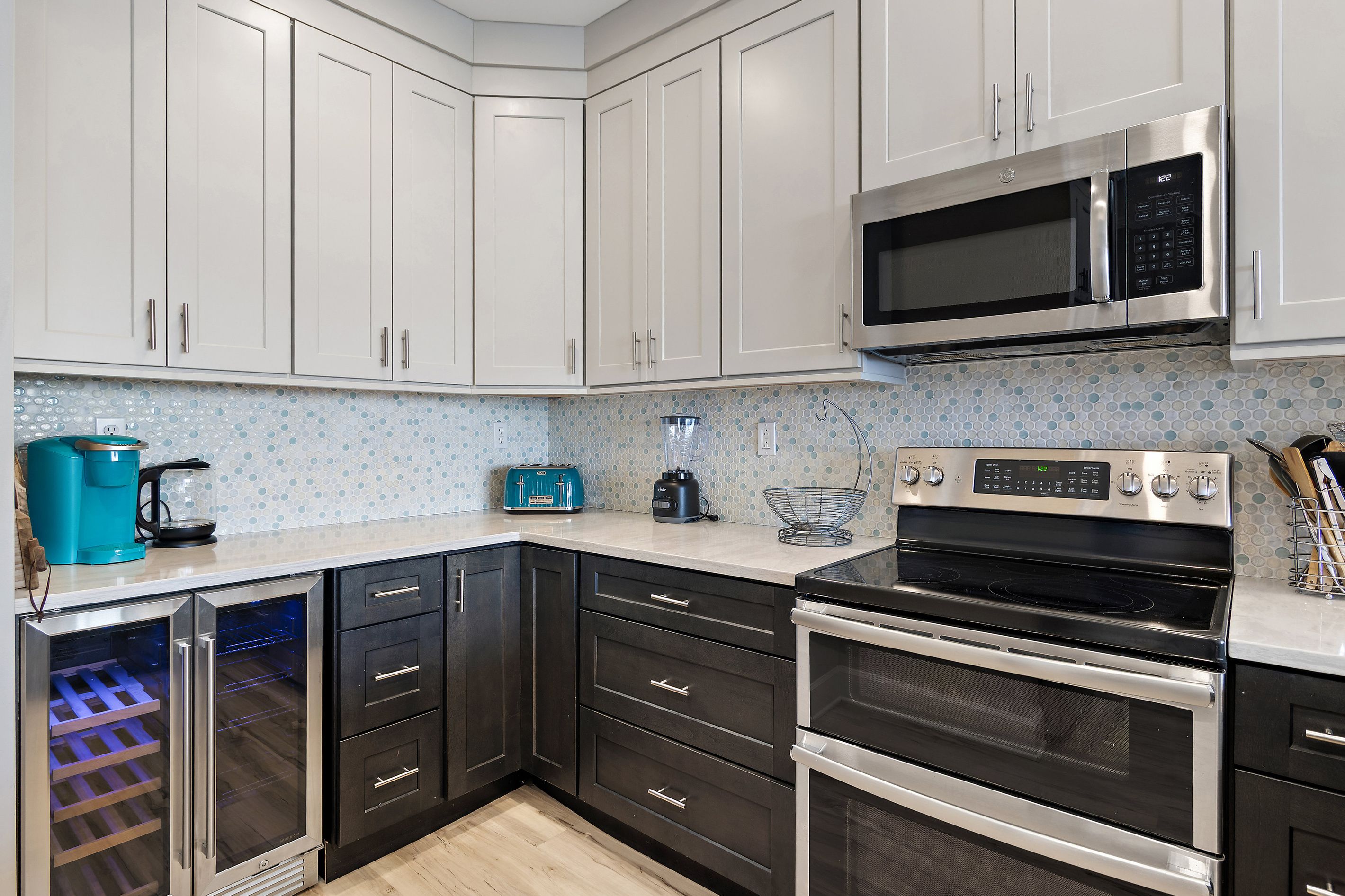 A modern kitchen with white cabinets, a microwave, a toaster, and an oven.