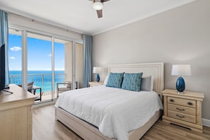 A hotel room with a large bed, two bedside tables, a desk, and a view of the ocean. - Luxurious Direct Gulf Front Penthouse (Miramar Beach)