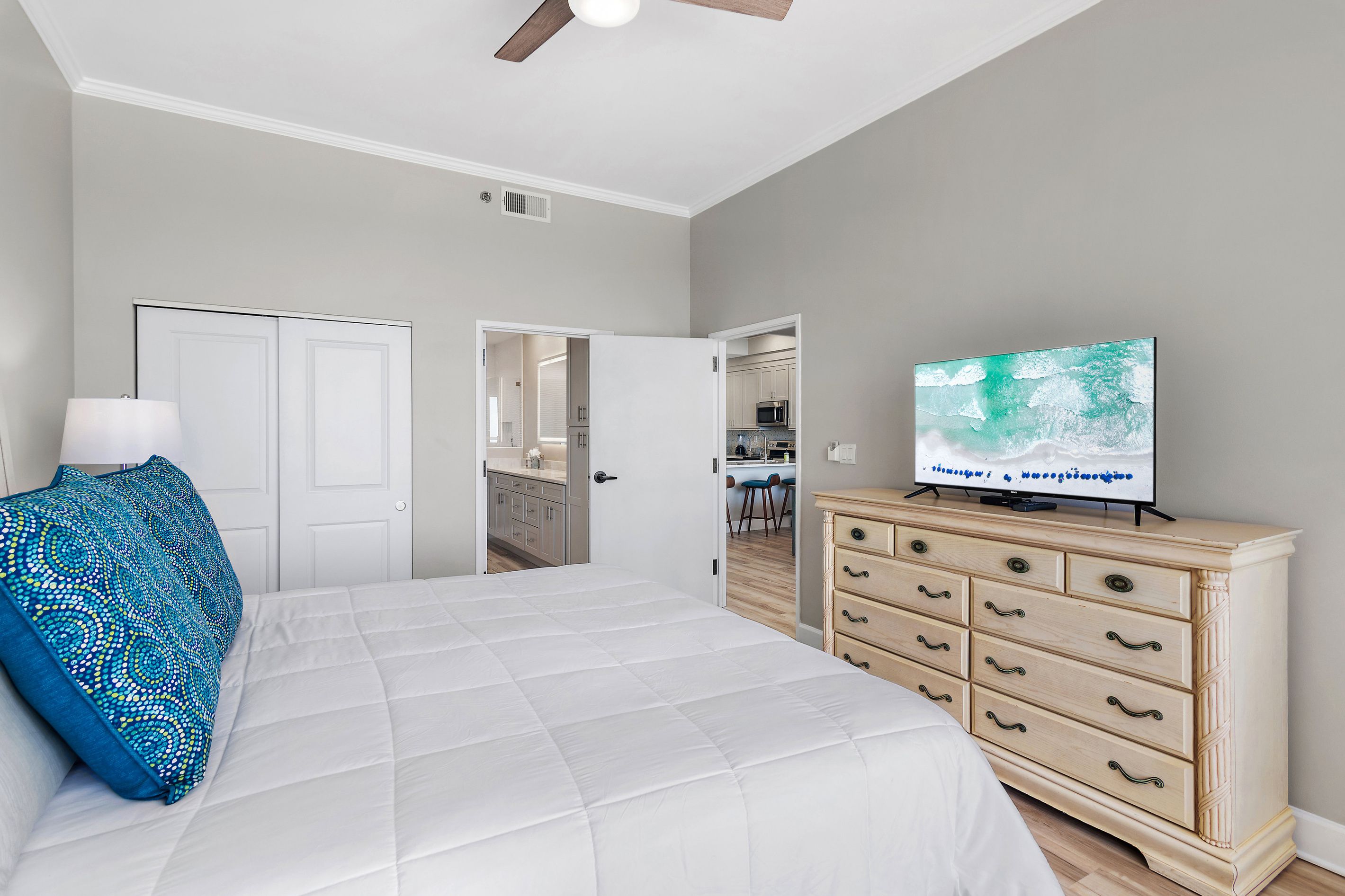 A bedroom with a bed, a dresser, a television, and a ceiling fan.