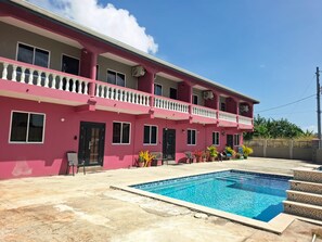 A two-story building with a swimming pool in the foreground. - Canaan Beauty (Golden Grove)