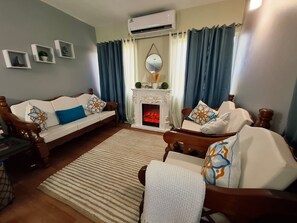 A living room with a fireplace, two sofas, a coffee table, and a rug. - Canaan Beauty (Golden Grove)
