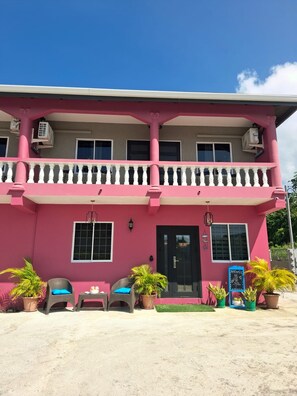 A two-story building with a balcony, potted plants, and outdoor seating. - Canaan Beauty (Golden Grove)