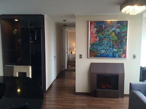 A modern living room with a fireplace, a large abstract painting, and a dining area with a black table. - Viña Lounge (Vina del Mar)