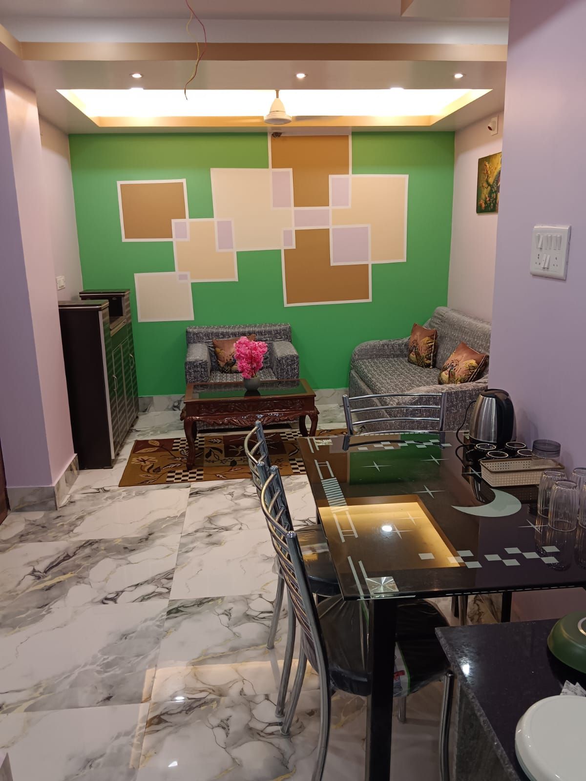 A dining area with a marble floor, a dining table with chairs, a sofa, and a coffee machine.