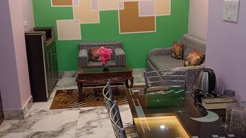 A dining area with a marble floor, a dining table with chairs, a sofa, and a coffee machine.