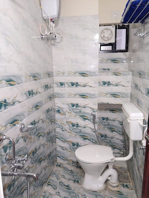 Une salle de bain équipée de toilettes, d’une douche et d’un chauffe-eau.