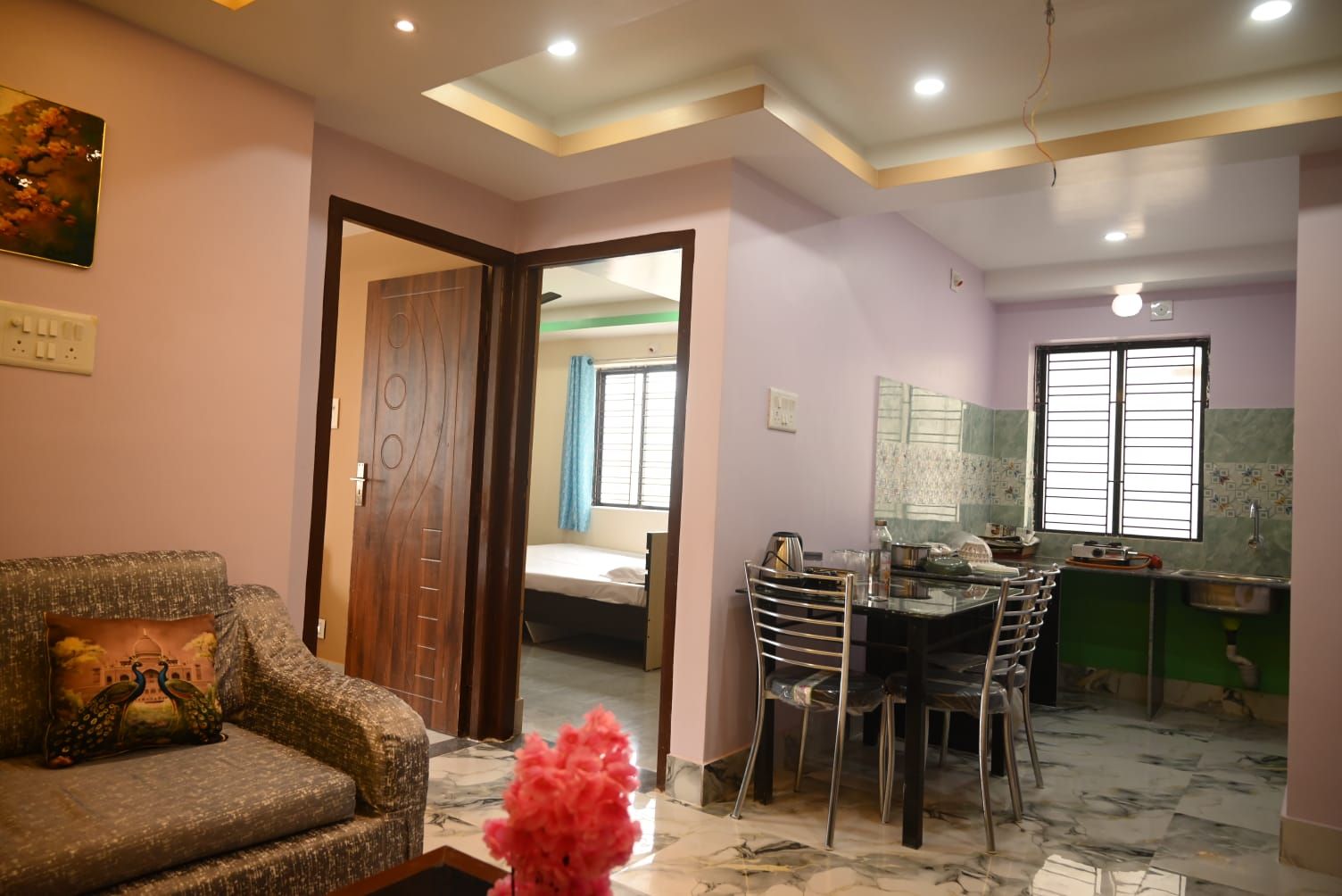 A living room with a sofa, a dining table with chairs, a kitchen area with a sink, and a bedroom with a bed.